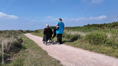 Devon England UK. 30.09.2024. Video. Elderly man using an electric wheelchair along a coastal pth in south Devon UK. photo