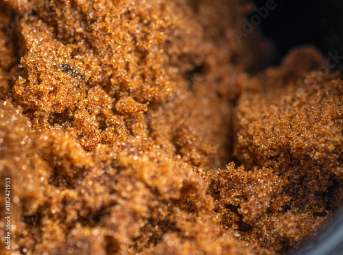 Close-up of brown demerera sugar granules, showing intricate details,with a dark background.