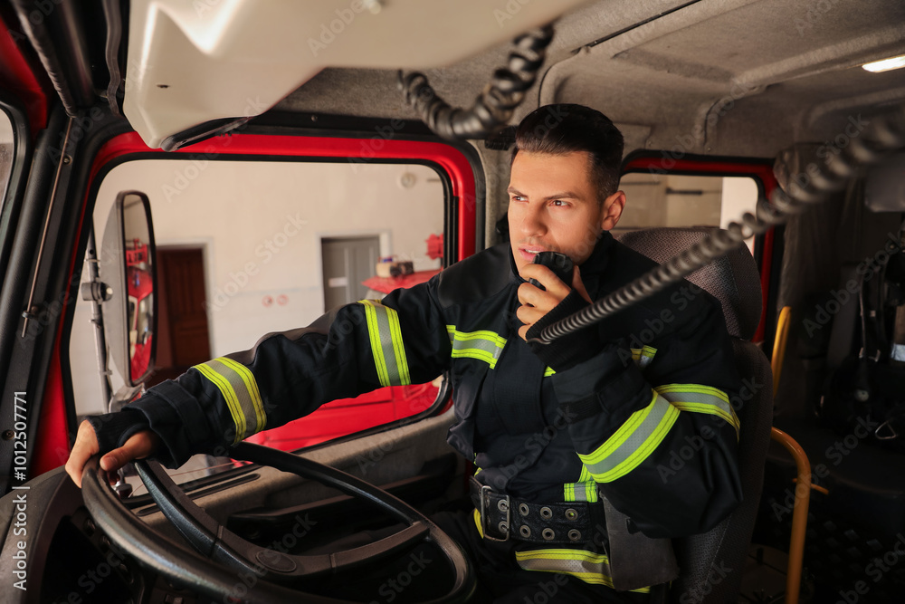 Naklejka premium Firefighter using radio set while driving fire truck