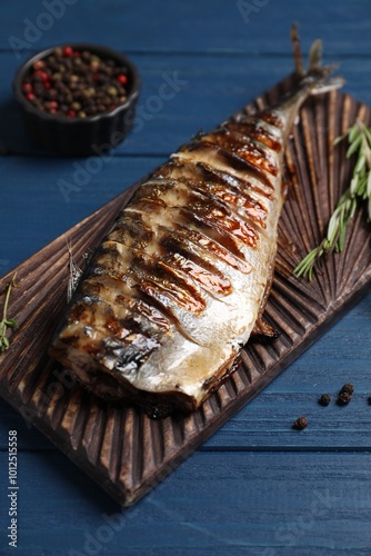 Konstfotografi Board with delicious grilled mackerel, peppercorns and rosemary on blue wooden t