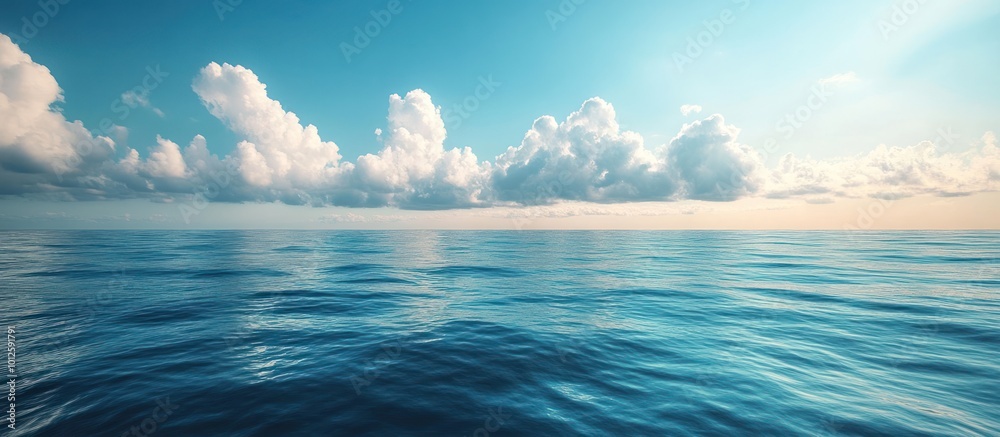 Fototapeta premium Tranquil blue ocean surface with white clouds in the blue sky.
