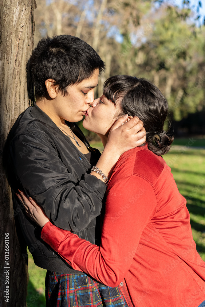 LGBT couple of women sharing a passionate kiss against a tree