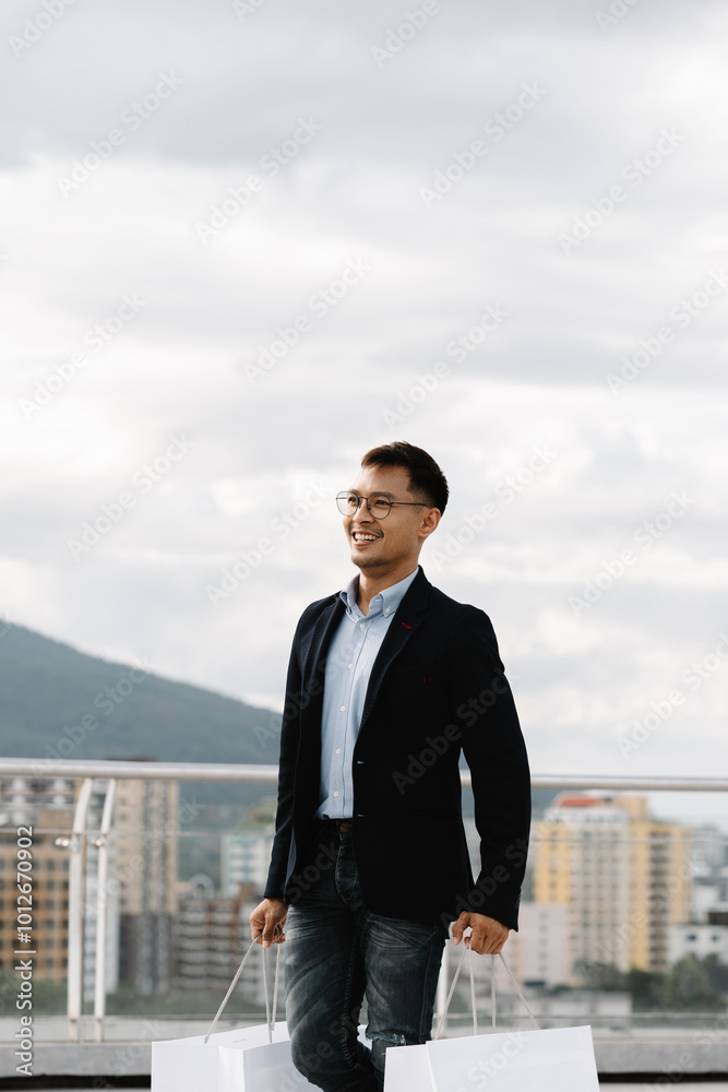 Joyful Shopper on City Rooftop: A stylish young man strolls across a rooftop terrace, carrying shopping bags, enjoying a sunny day in the city. Joyful Shopper on City Rooftop: A stylish young man strolls across a rooftop terrace, carrying shopping bags, enjoying a sunny day in the city.