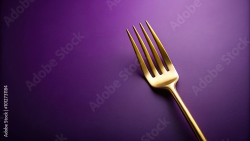 Fork with golden prongs on purple background photo