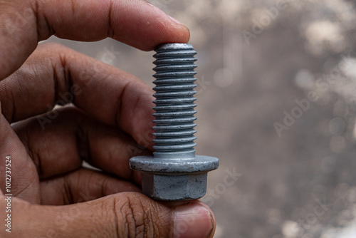 Close-up of a Mechanic's Hand Holding a Silver Bolt