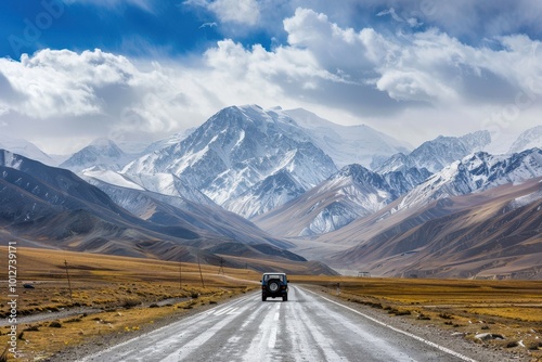 Mountain road snowy peaks in the distance off road car on the road