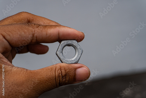 Close-up of a Mechanic's Hand Holding a Silver Nut