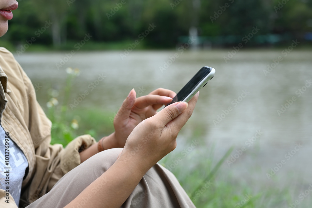 Young woman using mobile phone near lake. People, lifestyle and technology concept Young woman using mobile phone near lake. People, lifestyle and technology concept
