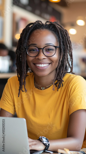 African-American woman glasses sitting table cafe working laptop
