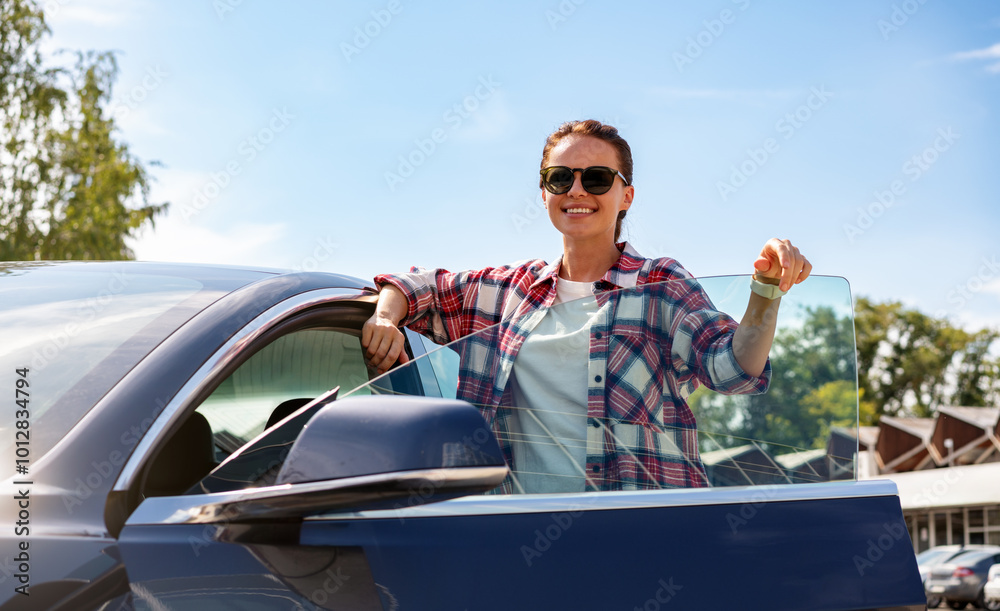 Attractive young woman standing beside her new electric car outdoors during summer. Car rental service, car-sharing. Attractive young woman standing beside her new electric car outdoors during summer. Car rental service, car-sharing.