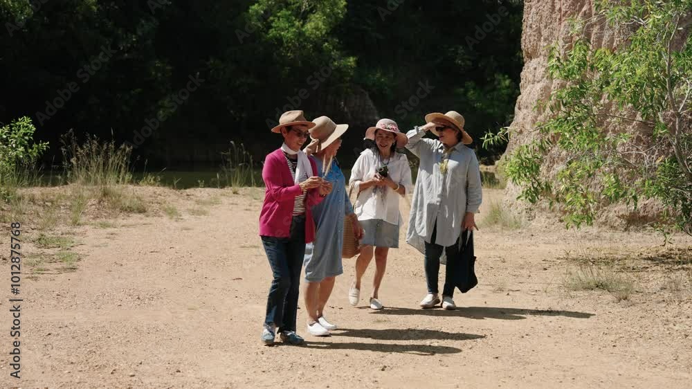Elderly women are in good health, come admire their favorite nature, take walk together along riverbank surrounded by beautiful high rocks, woman holds beautiful flower in hand happy smile. Elderly women are in good health, come admire their favorite nature, take walk together along riverbank surrounded by beautiful high rocks, woman holds beautiful flower in hand happy smile.