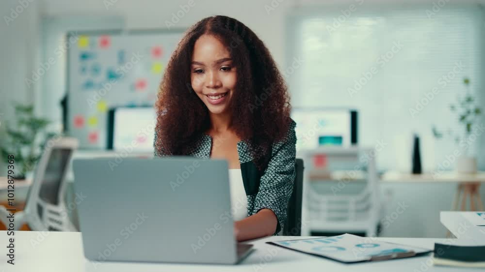 Smiling african american manager works on a laptop at her desk in a modern office. The atmosphere reflects professionalism and positivity in a corporate environment Smiling african american manager works on a laptop at her desk in a modern office. The atmosphere reflects professionalism and positivity in a corporate environment
