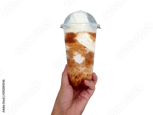 Hand holding American ice cream float with cola in tall take away plastic glass isolated on white background with clipping path and copy space. Root beer float with vanilla soft ice cream. photo