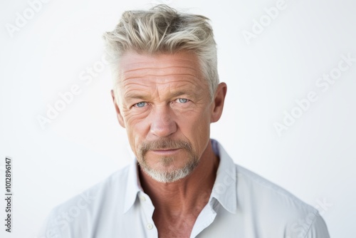 Portrait of handsome mature man looking at camera while standing against white background