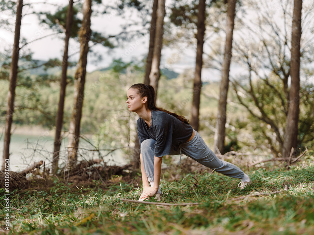 Focused young woman practicing yoga outdoors in a serene forest, demonstrating a dynamic lunge pose amidst nature Health and wellness concept Focused young woman practicing yoga outdoors in a serene forest, demonstrating a dynamic lunge pose amidst nature Health and wellness concept