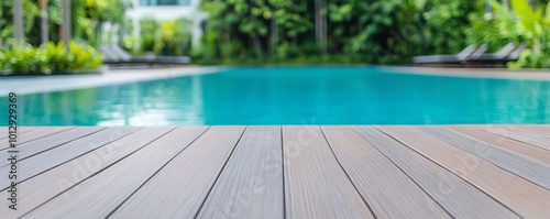 Wooden deck by tranquil pool, surrounded by lush greenery and bright blue water.