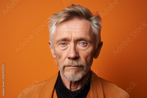 Portrait of an elderly man with a beard on an orange background