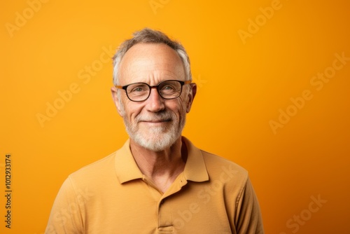 Portrait of a happy senior man in glasses on a yellow background