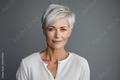 Portrait of an attractive mature woman with grey hair, isolated on grey background