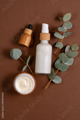 anti-aging collagen facial serum in bamboo bottle and face cream on brown background with eucalyptus. Natural Organic Cosmetic Beauty Concept. Mockup for branding photo