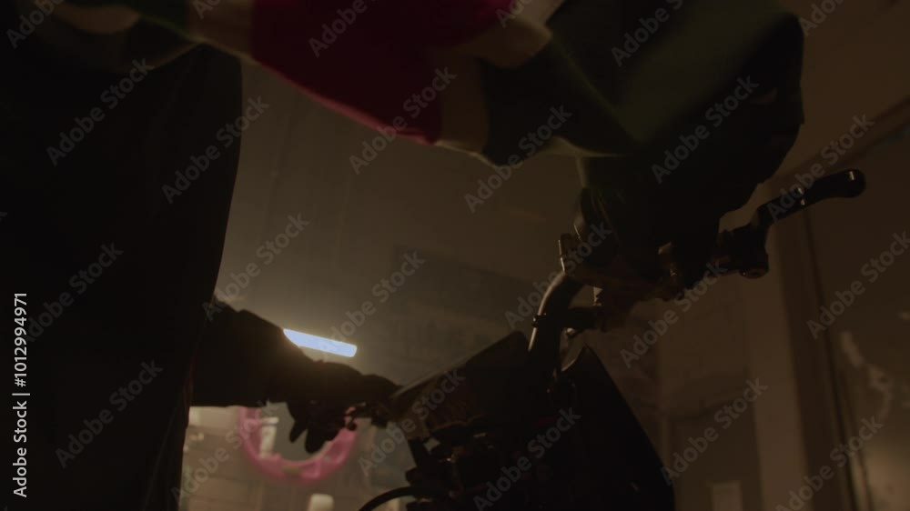 Man wearing motor gloves assertively twists throttle to test speed of combustion engine. Rider evaluates performance of new motorcycle at darkness Man wearing motor gloves assertively twists throttle to test speed of combustion engine. Rider evaluates performance of new motorcycle at darkness