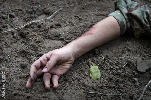 Hand of a wounded soldier on the ground photo