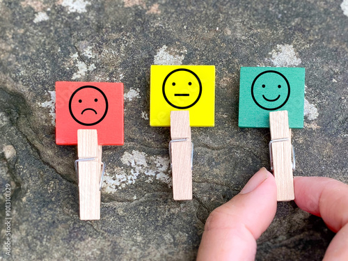 Hand pick out happy emoji. Smiley feedback rating icon on wooden square background. Service Rating Concept.