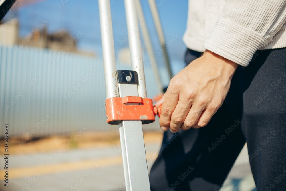 Engineer or worker hand adjusting tripod leg high for optical level