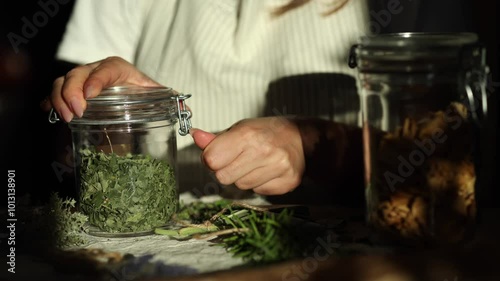 Woman opens a jar of dried mint. Work with herbs. Process 