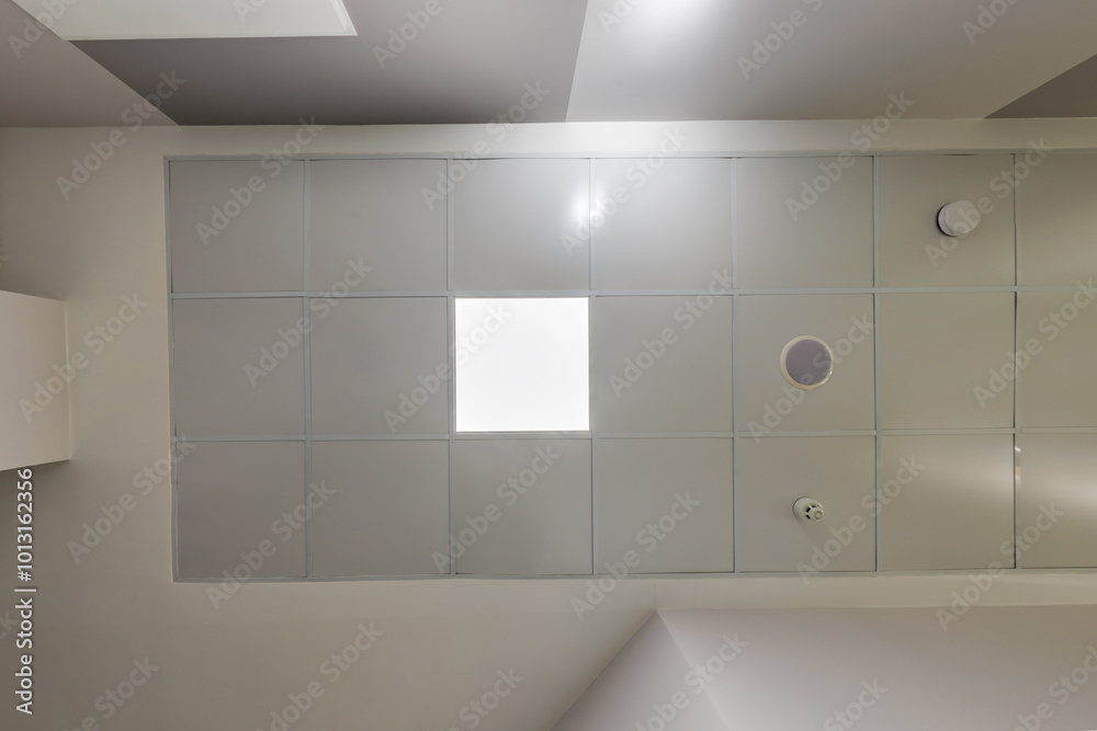 cassette stretched or suspended ceiling with square halogen spots lamps and drywall construction in empty room in house or office. Looking up view cassette stretched or suspended ceiling with square halogen spots lamps and drywall construction in empty room in house or office. Looking up view