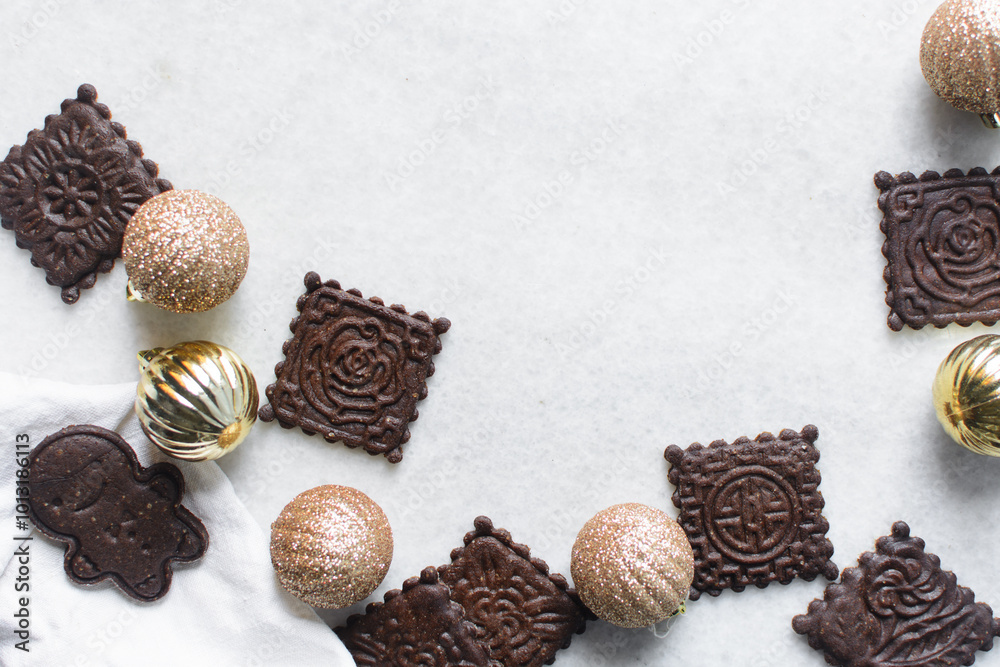 Overhead view of stamped molasses cookies and gold Christmas ornaments on a parchment lined baking tray, top view of embossed gingerbread cookies and gold Christmas baubles on a white background Overhead view of stamped molasses cookies and gold Christmas ornaments on a parchment lined baking tray, top view of embossed gingerbread cookies and gold Christmas baubles on a white background