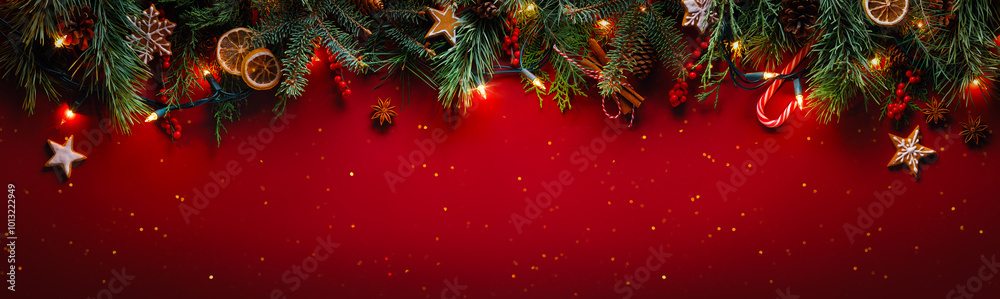 Christmas fir branches with gingerbread cookie on glittering red background with winter holiday lights