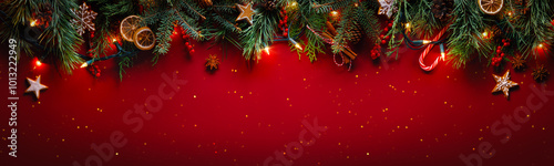 Obraz na płótnie Christmas fir branches with gingerbread cookie on glittering red background with winter holiday lights w salonie