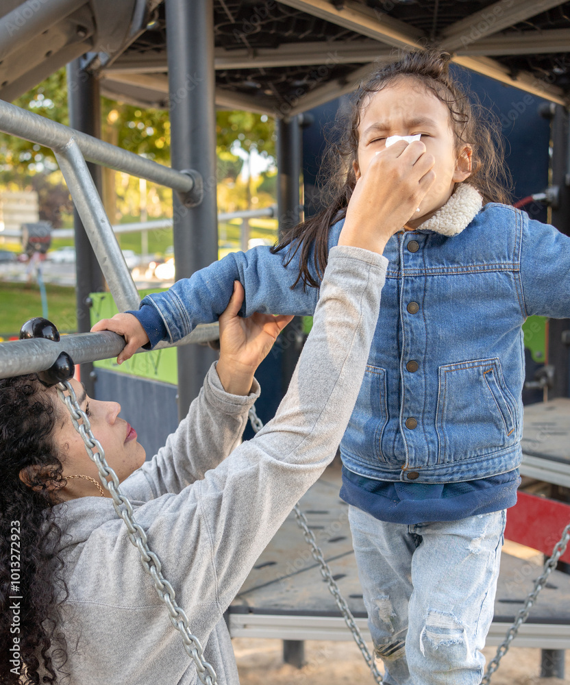 Dominican mother blowing nose of her sick son outdoors in autumn Dominican mother blowing nose of her sick son outdoors in autumn