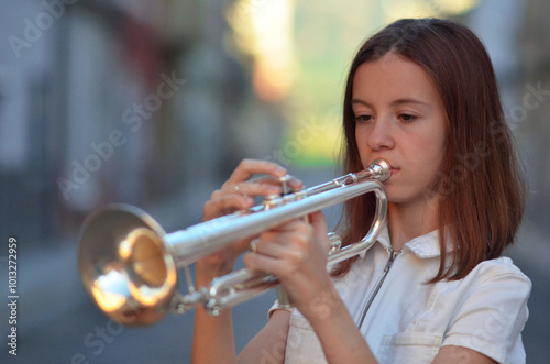 A young girl is playing a trumpet on a street