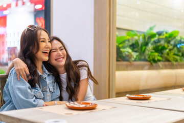 Family relationship, mother's day concept. Happy Asian mother and daughter enjoy outdoor lifestyle shopping and having lunch eating food together in restaurant at shopping mall on holiday vacation.