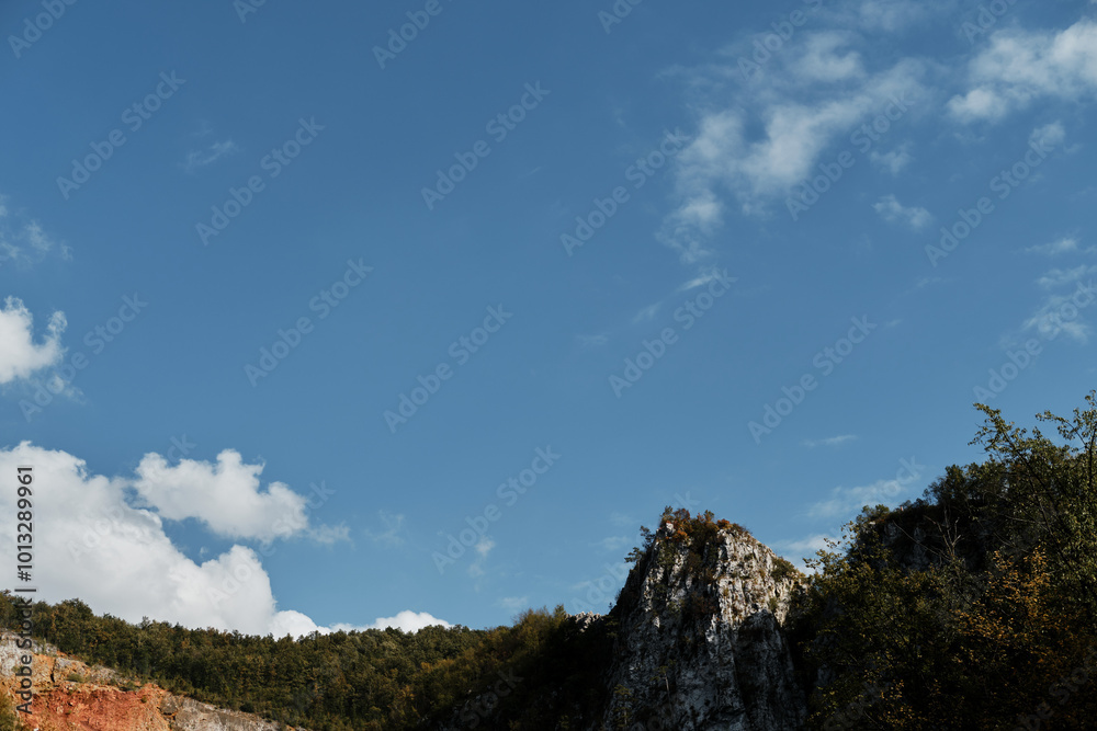 Beautiful view of the autumn forest and steep cliffs on a sunny day in a gorge near the town of Uzice in southern Serbia. The concept of peace and quiet. Blue sky with copy space.