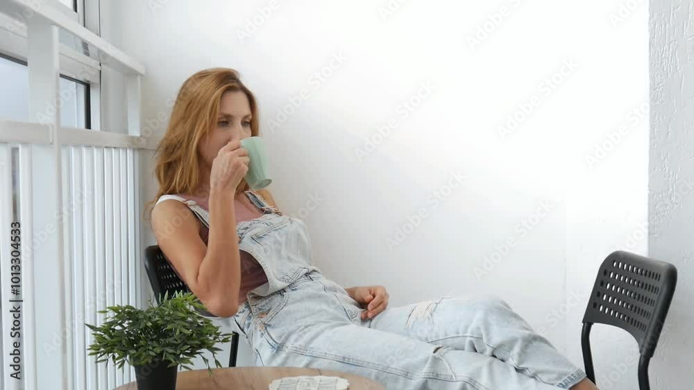 A cute young woman takes a sip of coffee and breaks into a happy smile A cute young woman takes a sip of coffee and breaks into a happy smile