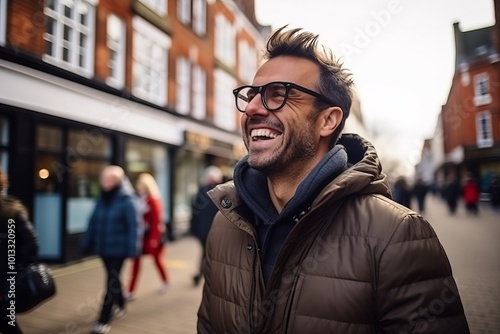 Portrait of a young man laughing in the street, wearing glasses