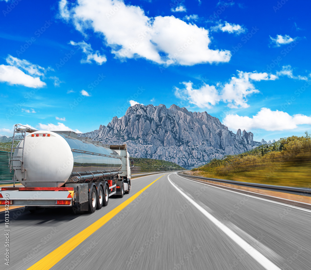 Obraz premium Fuel truck on a picturesque road. A silver tank truck transports fuel.