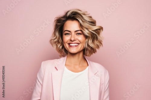 Portrait of a smiling young businesswoman standing against pink background.