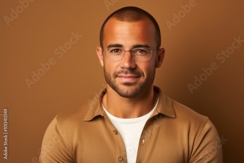 Portrait of a handsome young man in eyeglasses on brown background