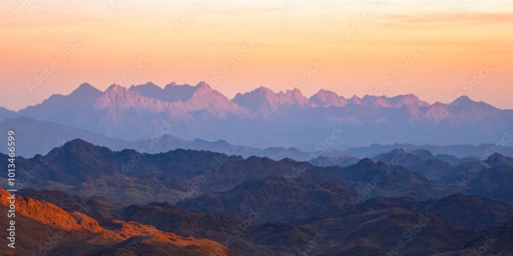 Mountain range at sunrise with soft colors and layers.