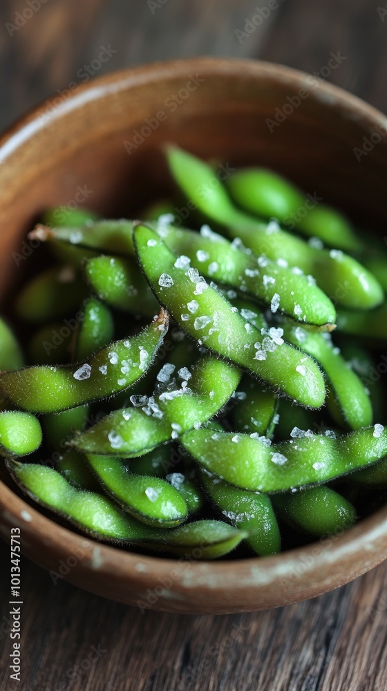 Fresh green edamame sprinkled with sea salt in a rustic wooden bowl, perfect for healthy snacking or culinary presentations.
