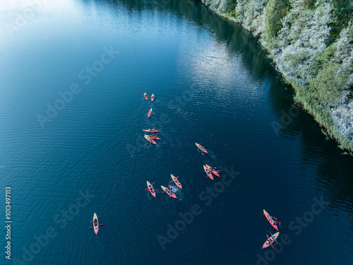 Aerial drone view of people kayaking on a lake surrounded by green forest. Kulka Reserve, Masuria, Poland. Sailing in red kayaks in the Masurian Lake District. Lake Lesk in the Kulka Reserve in Poland photo