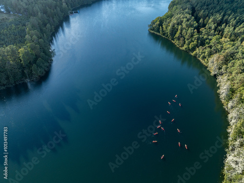 Aerial drone view of people kayaking on a lake surrounded by green forest. Kulka Reserve, Masuria, Poland. Sailing in red kayaks in the Masurian Lake District. Lake Lesk in the Kulka Reserve in Poland photo