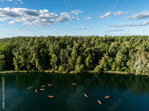 Aerial drone view of people kayaking on a lake surrounded by green forest. Kulka Reserve, Masuria, Poland. Sailing in red kayaks in the Masurian Lake District. Lake Lesk in the Kulka Reserve in Poland photo