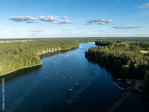 Aerial drone view of people kayaking on a lake surrounded by green forest. Kulka Reserve, Masuria, Poland. Sailing in red kayaks in the Masurian Lake District. Lake Lesk in the Kulka Reserve in Poland photo