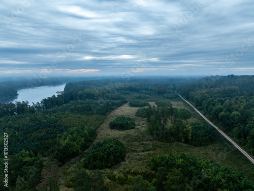 Aerial drone view of a lake surrounded by green forest. Big lake in the fog and clouds. Lake in the Masurian Lake District. Lake Lesk in the Kulka Reserve in Poland. Kulka Reserve, Masuria, Poland. photo