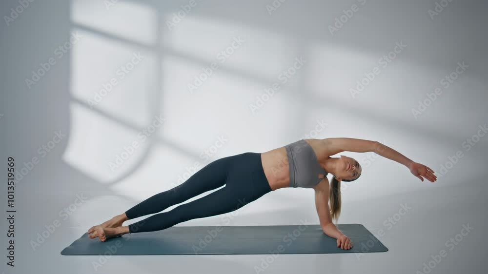 Fitness woman training body core muscles doing side plank on workout indoors